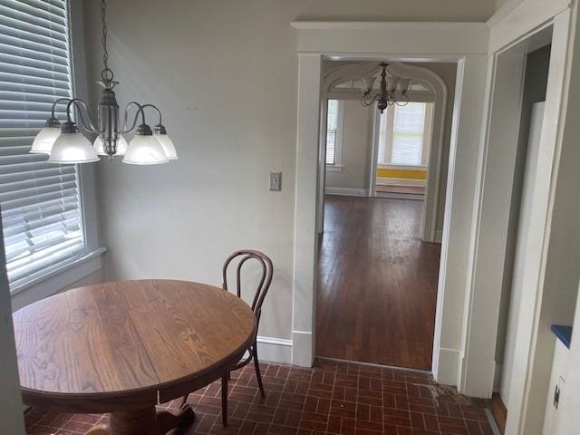 dining space with a chandelier, baseboards, and brick patterned flooring