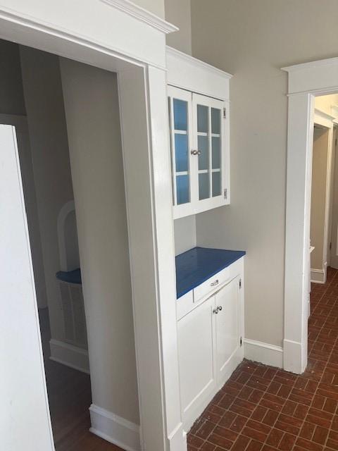 corridor with baseboards and brick patterned flooring
