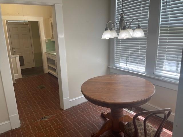 dining room featuring baseboards and brick patterned flooring