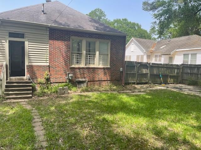 rear view of house with brick siding, entry steps, and a shingled roof