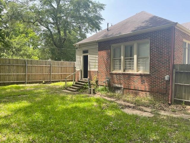 rear view of property with brick siding and roof with shingles