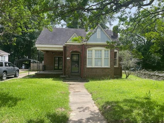 view of front of house featuring a front lawn, brick siding, and a detached carport