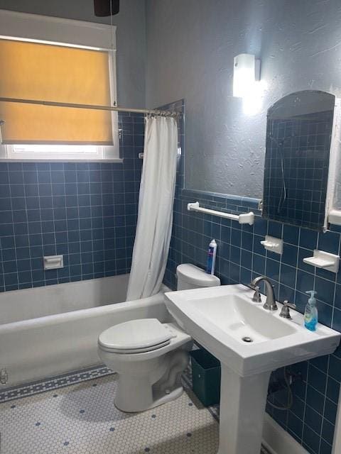 full bathroom with tile walls, toilet, shower / tub combo with curtain, and tile patterned flooring