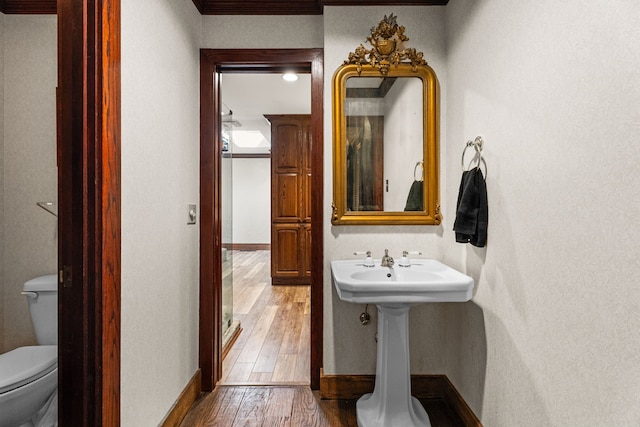 bathroom featuring toilet, hardwood / wood-style flooring, and baseboards