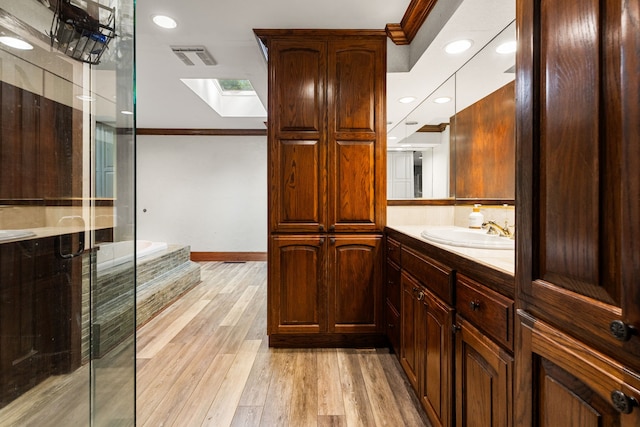 full bath featuring a skylight, a stall shower, crown molding, vanity, and wood finished floors