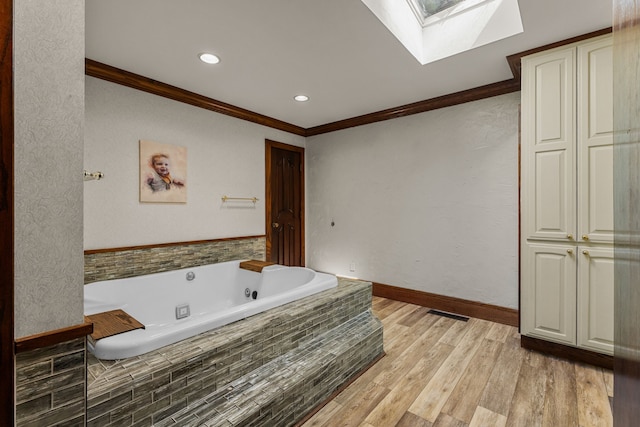 bathroom with a skylight, crown molding, a whirlpool tub, wood finished floors, and recessed lighting