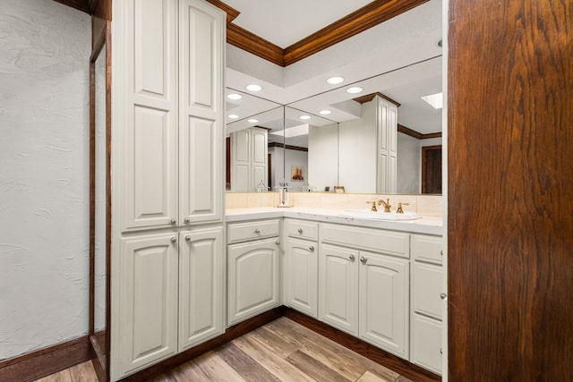 full bathroom with ornamental molding, a textured wall, wood finished floors, double vanity, and recessed lighting