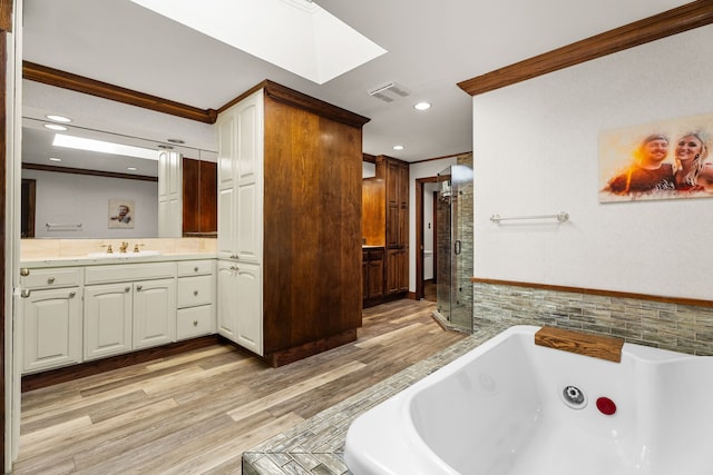 bathroom featuring ornamental molding, a tub with jets, wood finished floors, vanity, and a shower stall