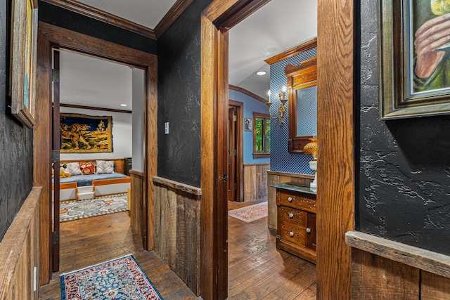hallway featuring crown molding, wood-type flooring, lofted ceiling, and a wainscoted wall