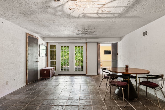 dining space featuring a textured wall, french doors, a textured ceiling, and baseboards