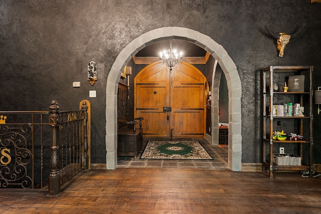 foyer entrance with arched walkways and hardwood / wood-style flooring
