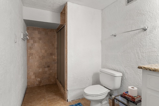 bathroom featuring a shower stall, toilet, tile patterned floors, and vanity
