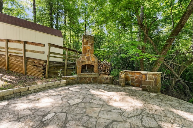 view of patio with an outdoor stone fireplace and fence