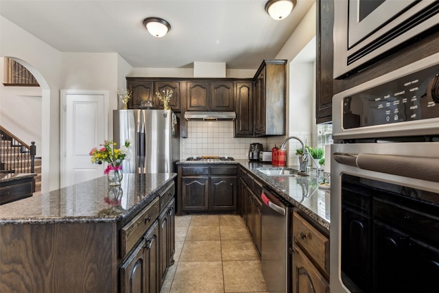 2314 Bob Sandlin Ln, Wylie, TX 75098 - kitchen with a sink, appliances with stainless steel finishes, tasteful backsplash, arched walkways, and dark brown cabinets