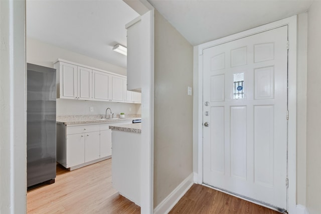 4914 Stagecoach Ln, Garland, TX 75043 - kitchen with light wood-style floors, light countertops, a sink, white cabinetry, and baseboards