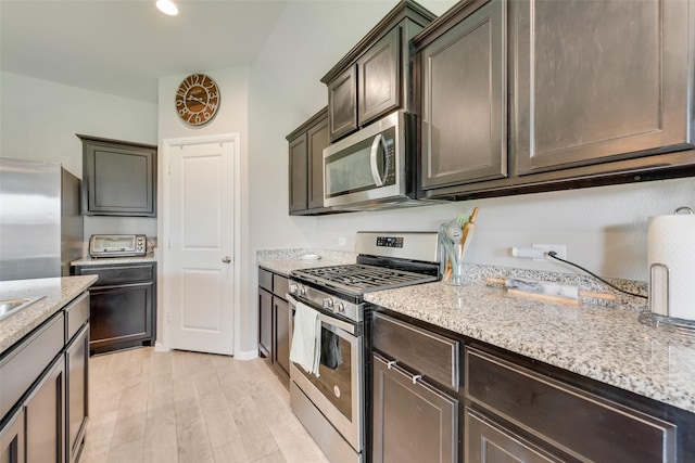 6128 Blacksmith Ave, Fort Worth, TX 76179 - kitchen with stainless steel appliances, light stone countertops, dark brown cabinetry, and light wood-style flooring