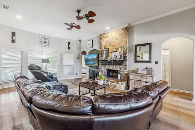 301 Shepherd Ln, Royse City, TX 75189 - living room featuring arched walkways, ornamental molding, a stone fireplace, baseboards, and light wood-style flooring