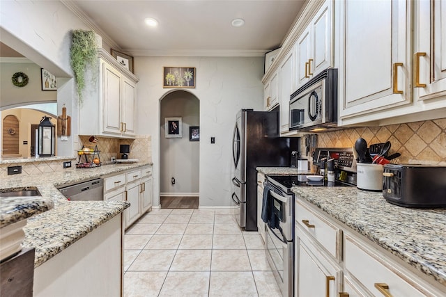 301 Shepherd Ln, Royse City, TX 75189 - kitchen with appliances with stainless steel finishes, arched walkways, tasteful backsplash, light stone countertops, and ornamental molding
