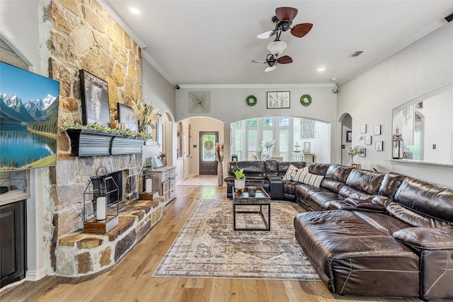 301 Shepherd Ln, Royse City, TX 75189 - living area featuring a stone fireplace, ceiling fan, crown molding, arched walkways, and light wood-style flooring