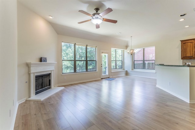 1716 Lake Way Dr, Little Elm, TX 75068 - unfurnished living room with a ceiling fan, a fireplace with raised hearth, a chandelier, light wood-style floors, and baseboards
