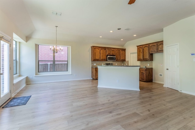 1716 Lake Way Dr, Little Elm, TX 75068 - kitchen with stainless steel microwave, vaulted ceiling, a chandelier, brown cabinets, and decorative backsplash