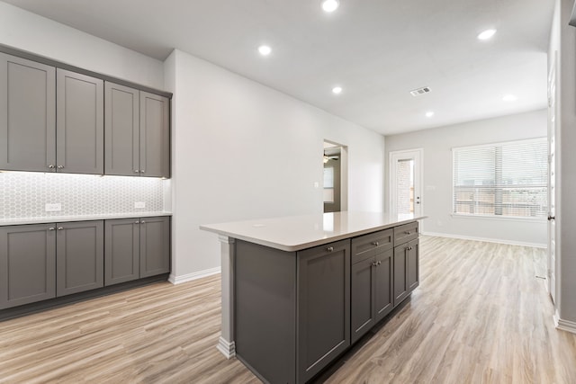 3510 Riley St, Fate, TX 75087 - kitchen featuring light wood-type flooring, a kitchen island, gray cabinetry, baseboards, and decorative backsplash