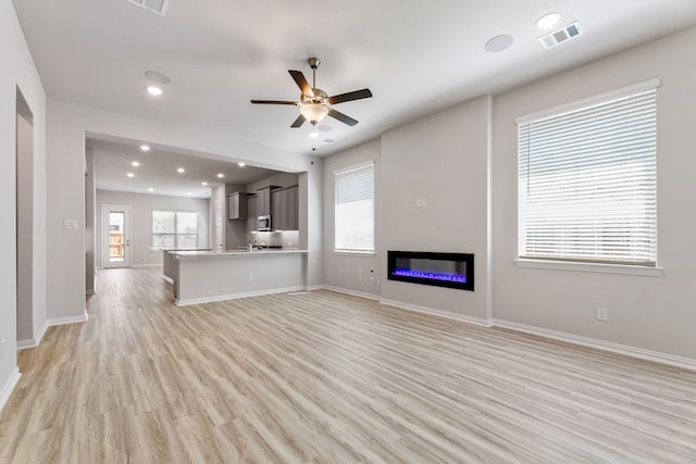 3510 Riley St, Fate, TX 75087 - unfurnished living room with ceiling fan, light wood-style flooring, baseboards, recessed lighting, and a glass covered fireplace