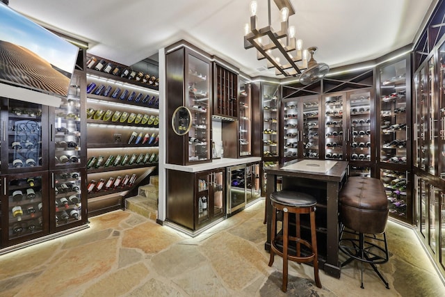 wine cellar featuring stone finish floors, a chandelier, and wine cooler