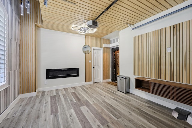 unfurnished living room featuring a glass covered fireplace, wood finished floors, and wooden ceiling