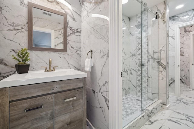 full bath featuring marble tiled floors, a marble finish shower, vanity, and tile walls