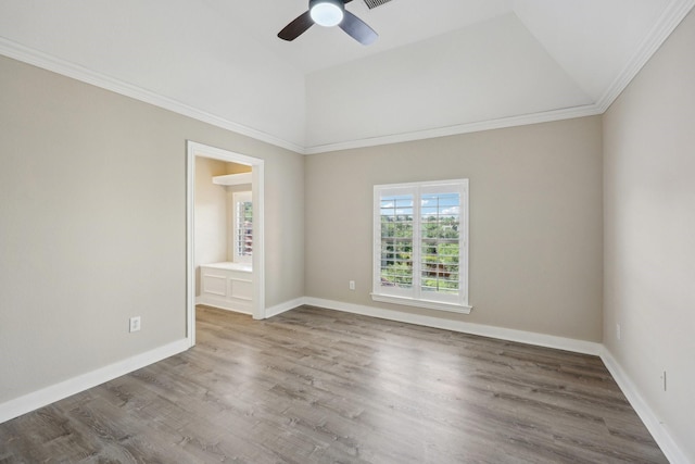 spare room featuring vaulted ceiling, ornamental molding, ceiling fan, wood finished floors, and baseboards