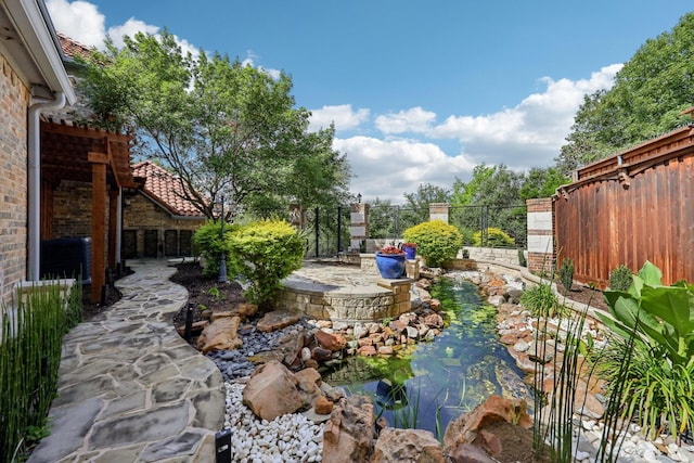 view of yard with a garden pond, fence, and a patio area
