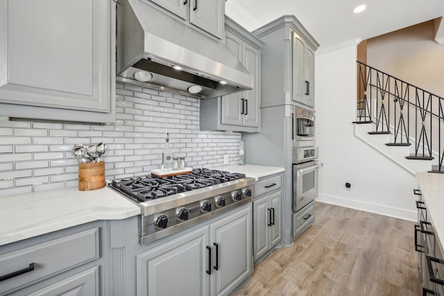 kitchen featuring gray cabinets, under cabinet range hood, appliances with stainless steel finishes, tasteful backsplash, and recessed lighting