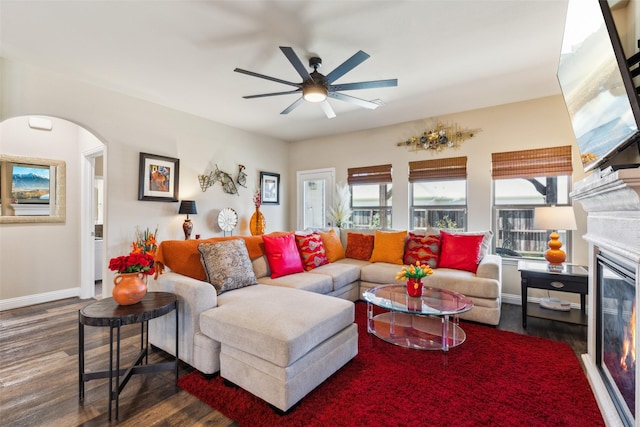 619 Comal Dr, Crandall, TX 75114 - living area featuring wood finished floors, ceiling fan, arched walkways, baseboards, and a glass covered fireplace