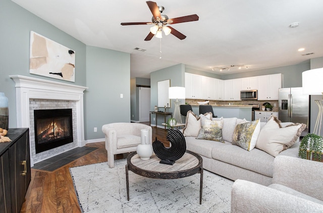 9305 Manassas Rdg, Mckinney, TX 75071 - living area featuring a ceiling fan, dark wood finished floors, a fireplace with flush hearth, and baseboards