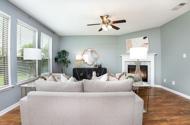 9305 Manassas Rdg, Mckinney, TX 75071 - living area with a warm lit fireplace, dark wood-style floors, a ceiling fan, and baseboards