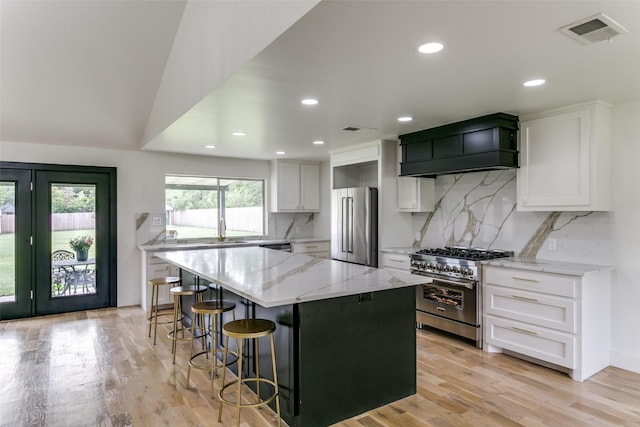 203 Oak Valley Dr, Colleyville, TX 76034 - kitchen featuring high quality appliances, custom exhaust hood, light stone counters, white cabinetry, and a kitchen island