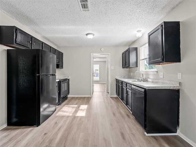 638 Matador Dr, Little Elm, TX 75068 - kitchen featuring black appliances, a sink, dark cabinetry, light wood-style flooring, and light countertops