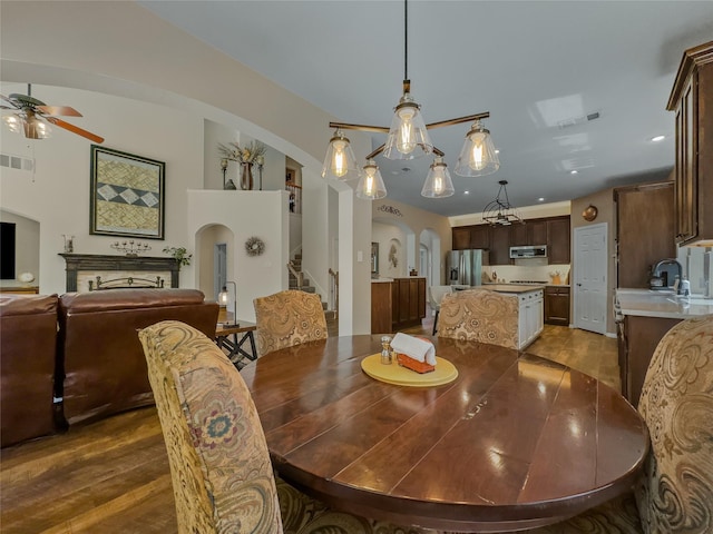 4305 Diplomacy Dr, Rowlett, TX 75089 - dining space featuring arched walkways, dark wood finished floors, a ceiling fan, and stairs