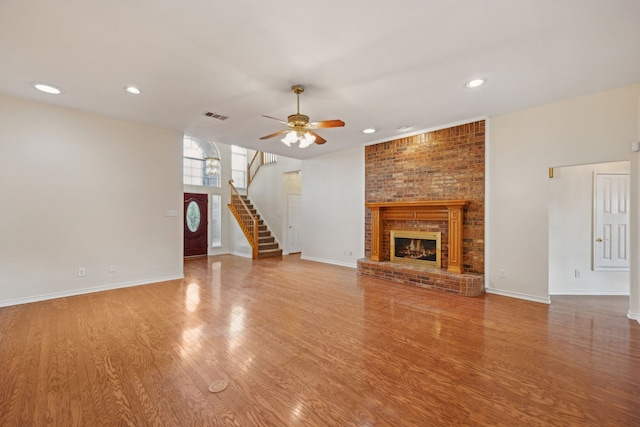 1086 Whispering Gln, Rockwall, TX 75087 - unfurnished living room featuring ceiling fan, stairs, a brick fireplace, wood finished floors, and recessed lighting