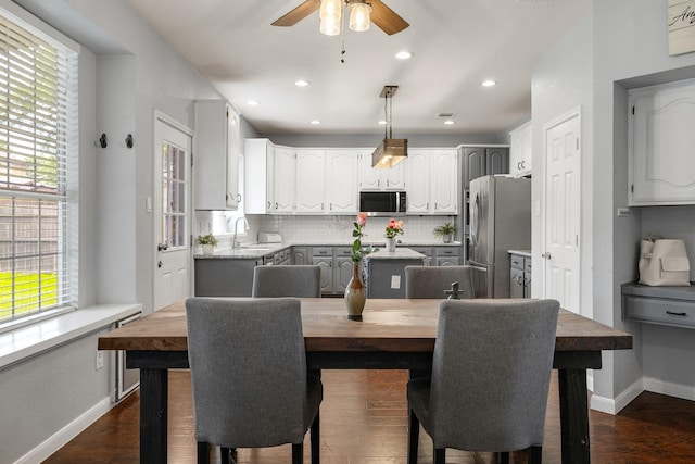 kitchen featuring appliances with stainless steel finishes, a sink, ceiling fan, decorative backsplash, and baseboards