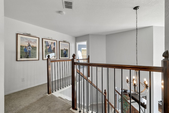 hallway with a chandelier, an upstairs landing, carpet, and baseboards