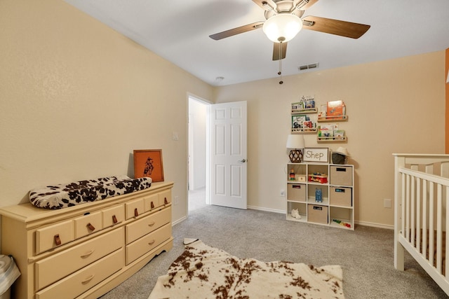 bedroom featuring carpet floors, a crib, a ceiling fan, and baseboards