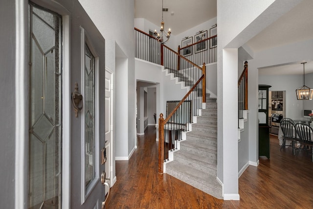 entryway with a chandelier, stairway, wood finished floors, baseboards, and a towering ceiling
