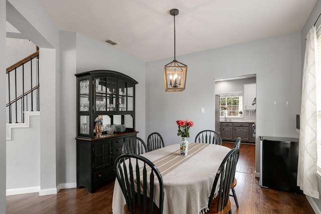 dining area featuring stairs, a chandelier, dark wood-style floors, and baseboards