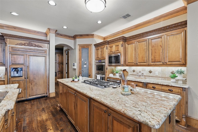 603 Comal Ct, Keller, TX 76248 - kitchen with arched walkways, light stone countertops, brown cabinetry, dark wood-style floors, and built in appliances