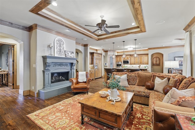 603 Comal Ct, Keller, TX 76248 - living area featuring arched walkways, a raised ceiling, ornamental molding, a ceiling fan, and dark wood-type flooring