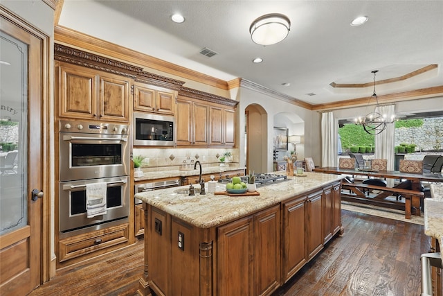 603 Comal Ct, Keller, TX 76248 - kitchen with appliances with stainless steel finishes, arched walkways, a sink, a kitchen island with sink, and light stone counters