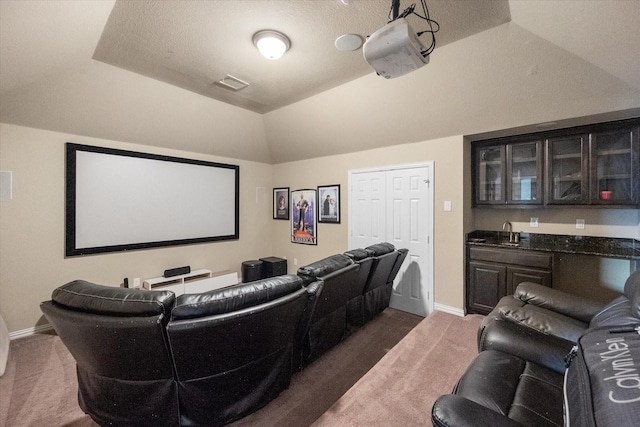 3449 Ava Dr, Midlothian, TX 76065 - home theater room featuring dark carpet, lofted ceiling, bar with sink, and baseboards