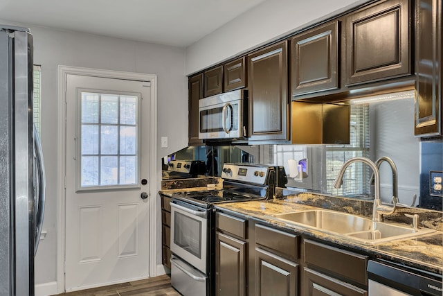 10240 Regal Oaks Dr Unit C, Dallas, TX 75230 - kitchen with appliances with stainless steel finishes, a sink, dark brown cabinetry, dark wood finished floors, and dark stone countertops